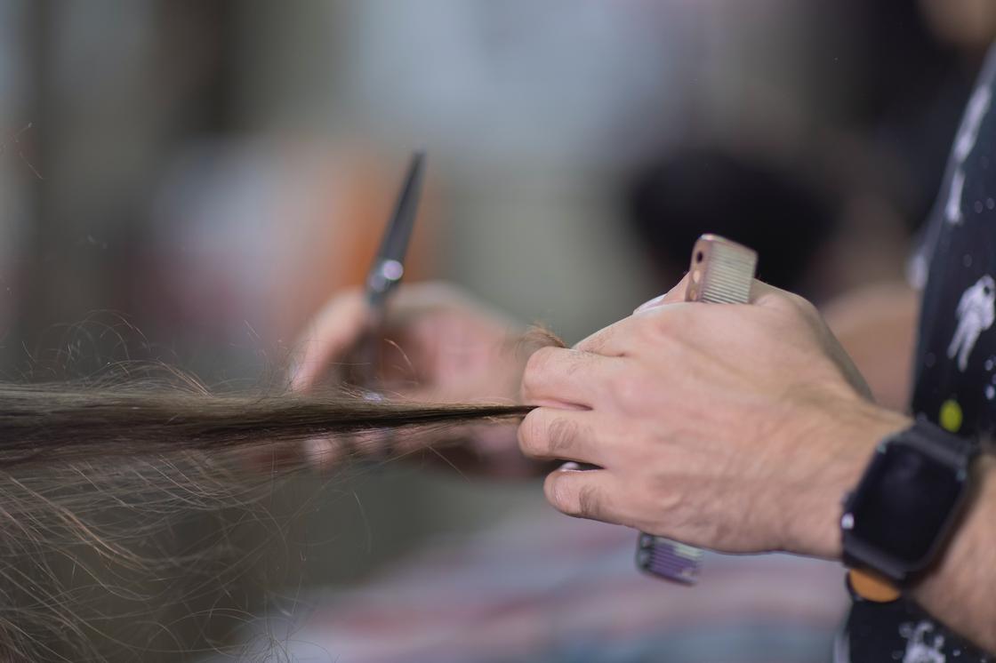 Парикмахер стрижет волосы